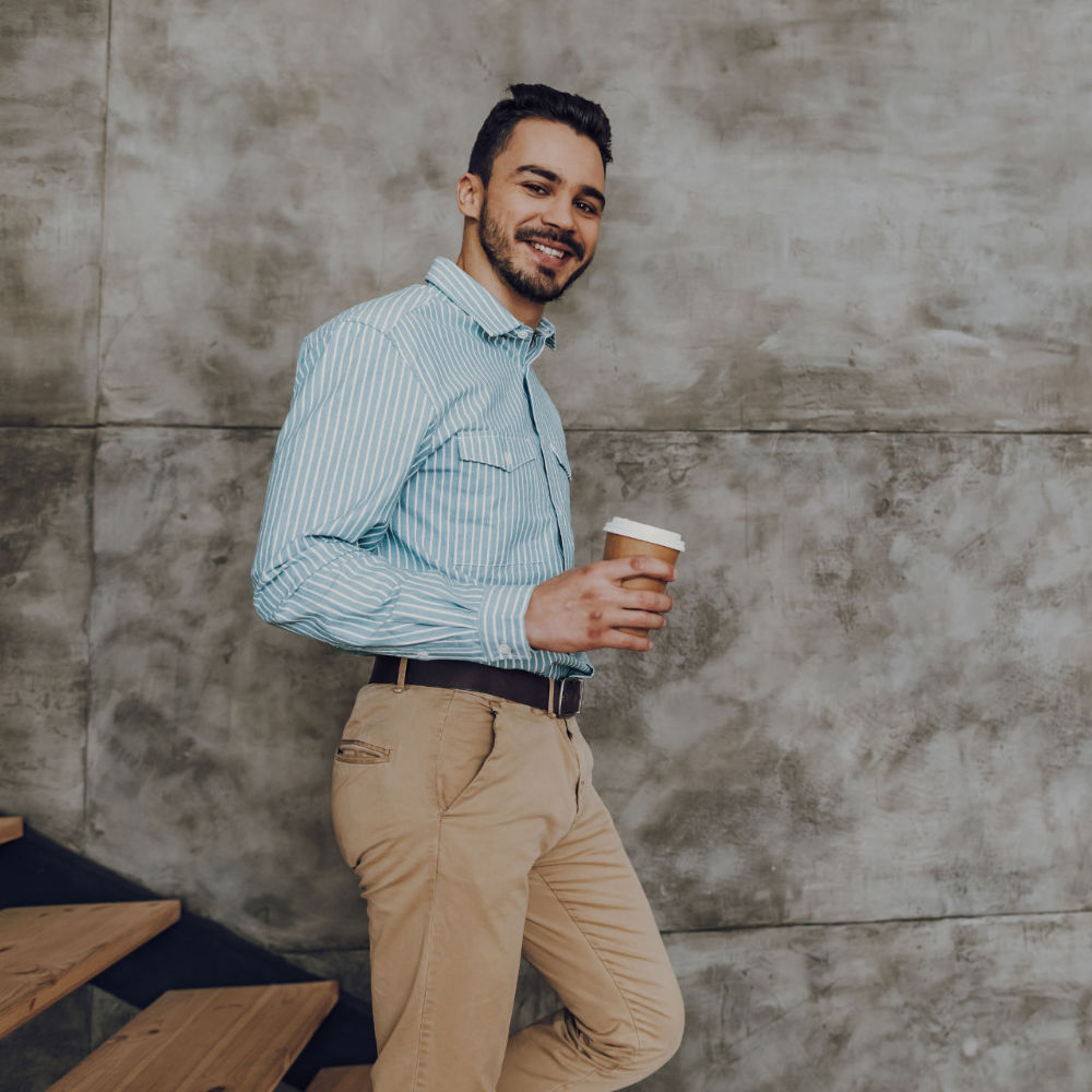 Happy man is enjoying cup of hot drink indoors